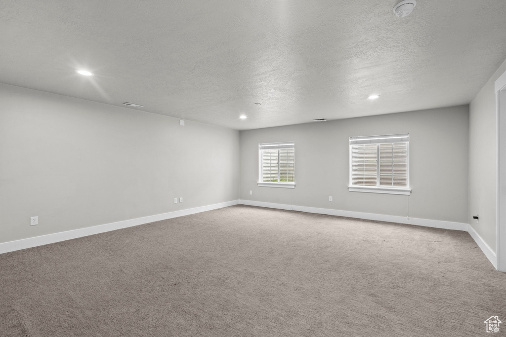 Carpeted spare room featuring a textured ceiling, a smoke detector, baseboards, and recessed lighting