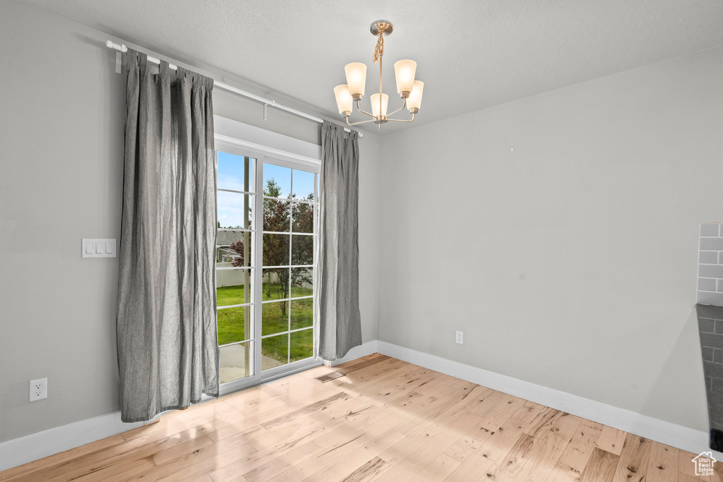Empty room with a chandelier, wood finished floors, and baseboards