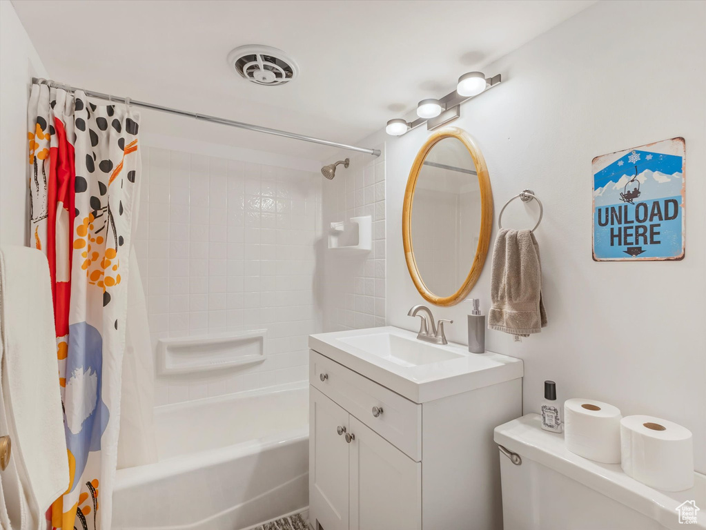 Bathroom featuring shower / bathtub combination with curtain, vanity, and toilet