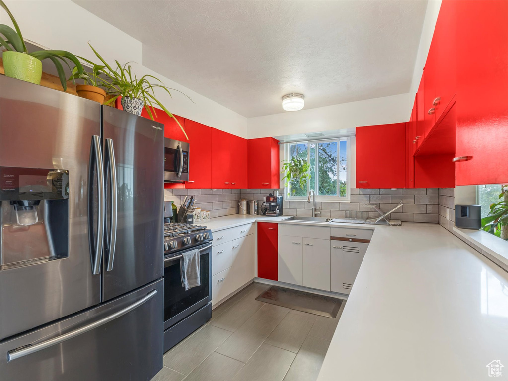 Kitchen featuring stainless steel appliances, a sink, healthy amount of natural light, and decorative backsplash