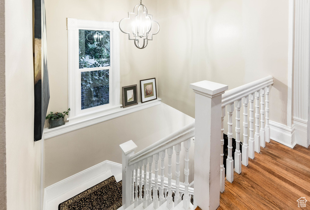 Staircase featuring wood finished floors and a chandelier