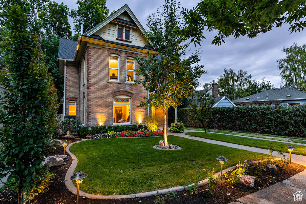 View of front of property featuring brick siding, a front lawn, and a shingled roof