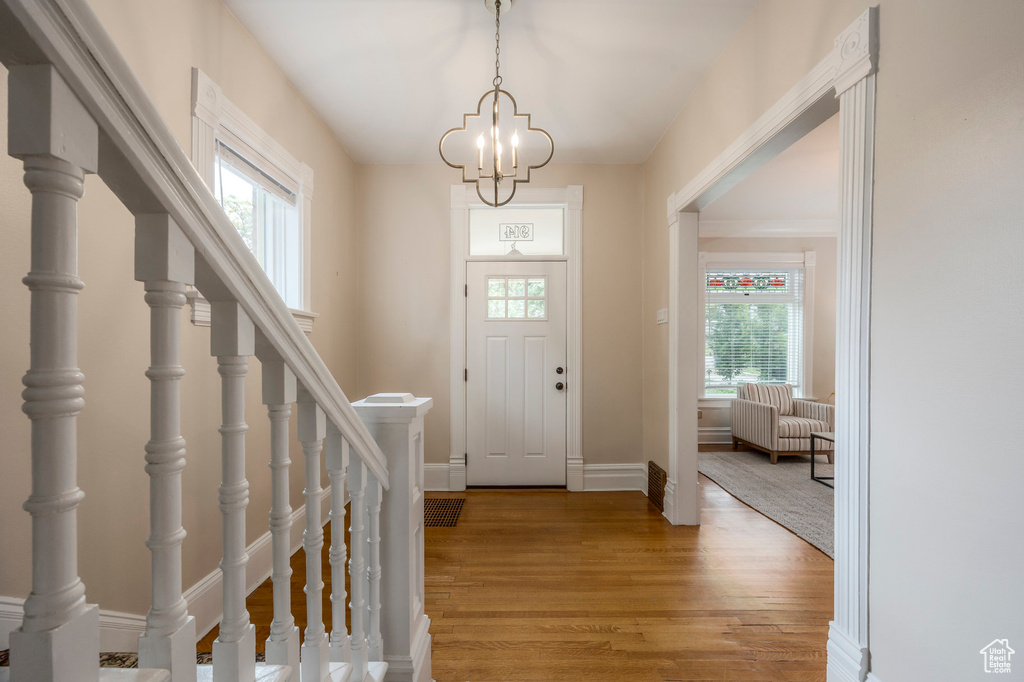 Entryway with light wood-type flooring, baseboards, a chandelier, and stairway
