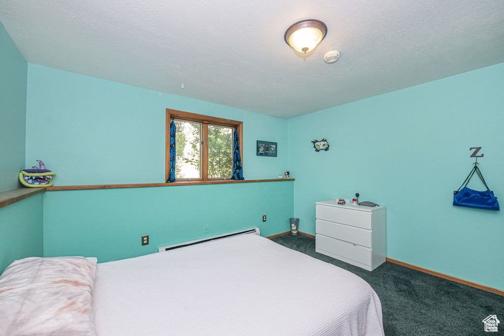 Carpeted bedroom with a baseboard radiator and baseboards