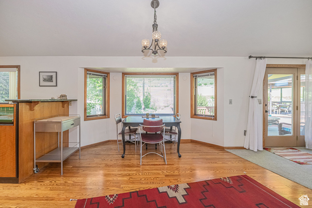 Dining area with baseboards, light wood finished floors, and a chandelier