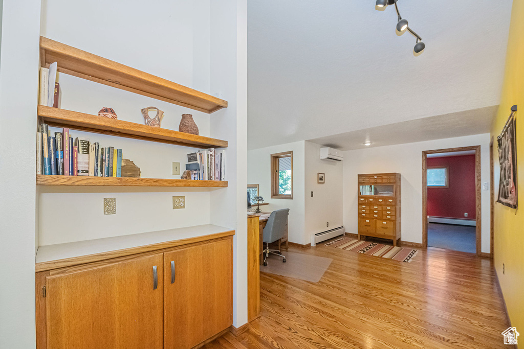 Entryway featuring a baseboard heating unit, an AC wall unit, built in study area, light wood finished floors, and a baseboard radiator