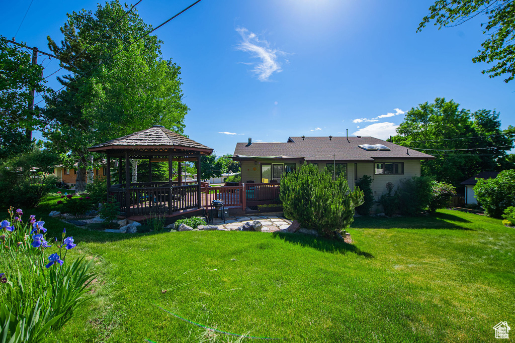 View of green lawn featuring a gazebo and a deck
