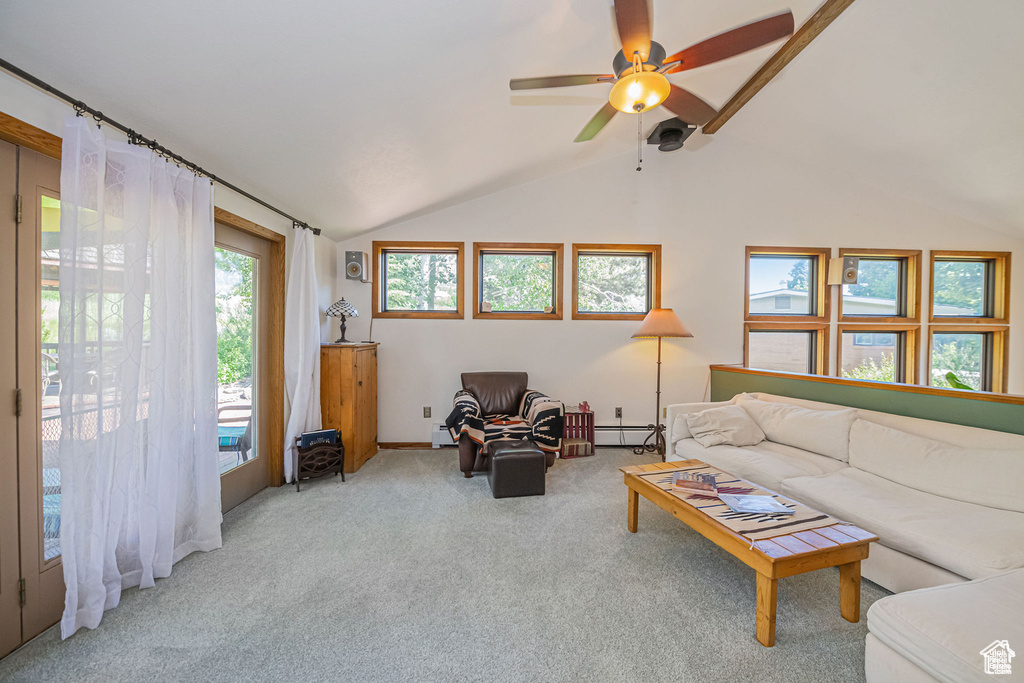 Carpeted living room with baseboard heating, vaulted ceiling, and ceiling fan