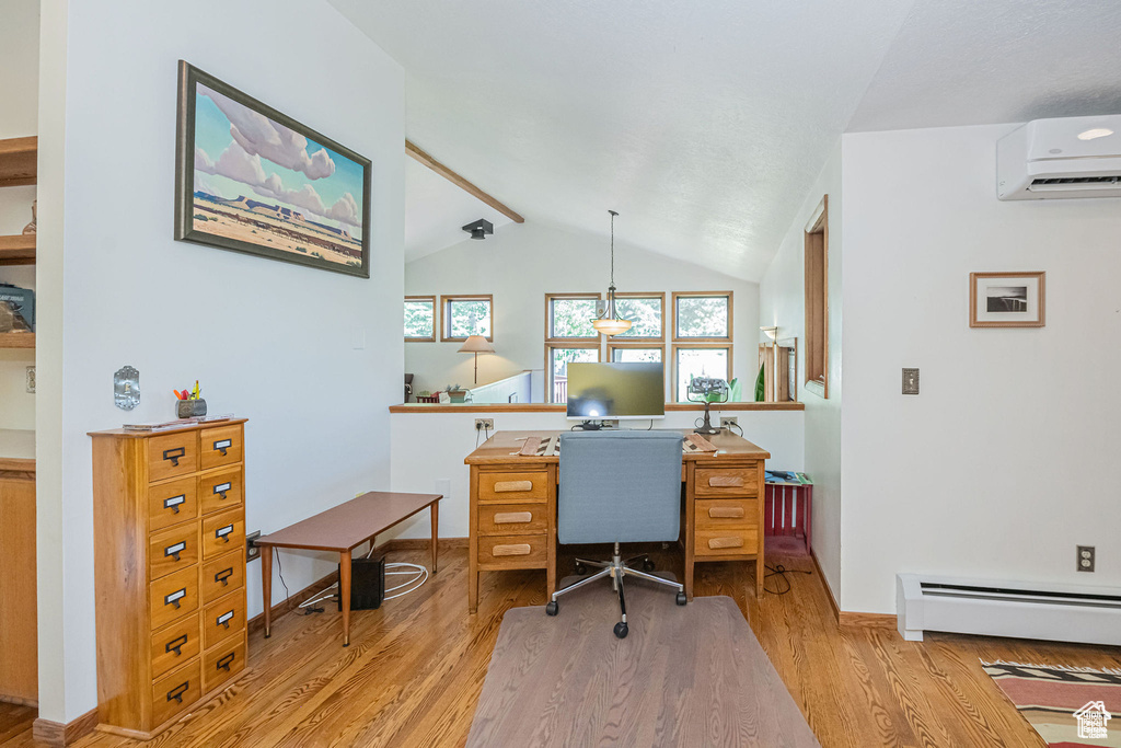 Office area featuring an AC wall unit, wood finished floors, a baseboard heating unit, and baseboards