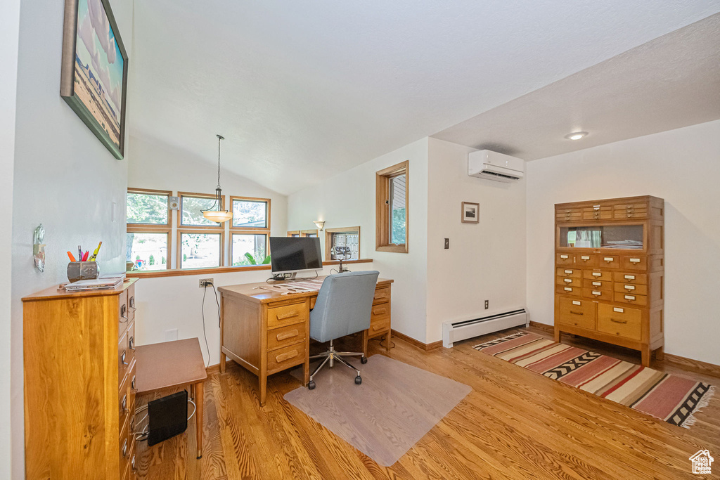 Home office featuring baseboard heating, light wood-type flooring, a wall mounted AC, baseboards, and lofted ceiling