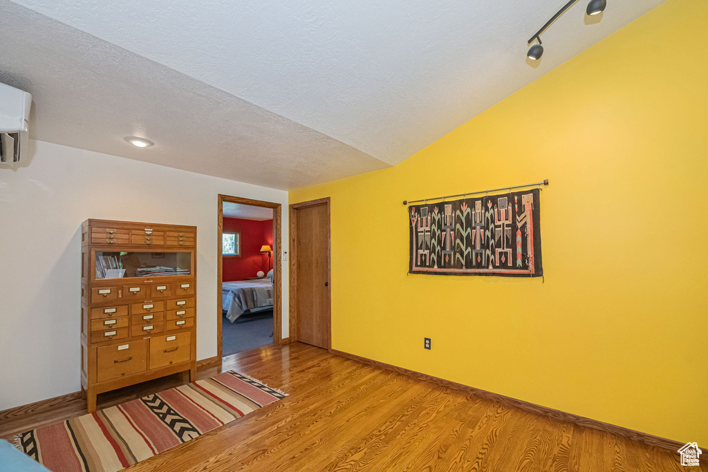 Spare room with wood finished floors, a textured ceiling, and a wall unit AC
