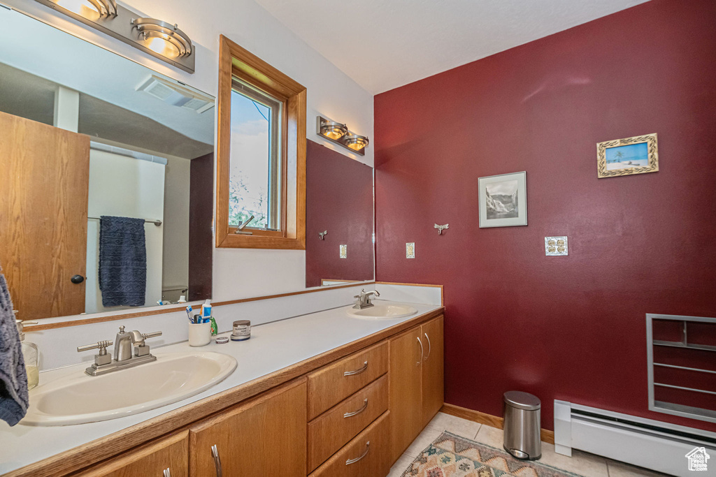 Full bathroom with a baseboard heating unit, tile patterned floors, double vanity, and baseboards