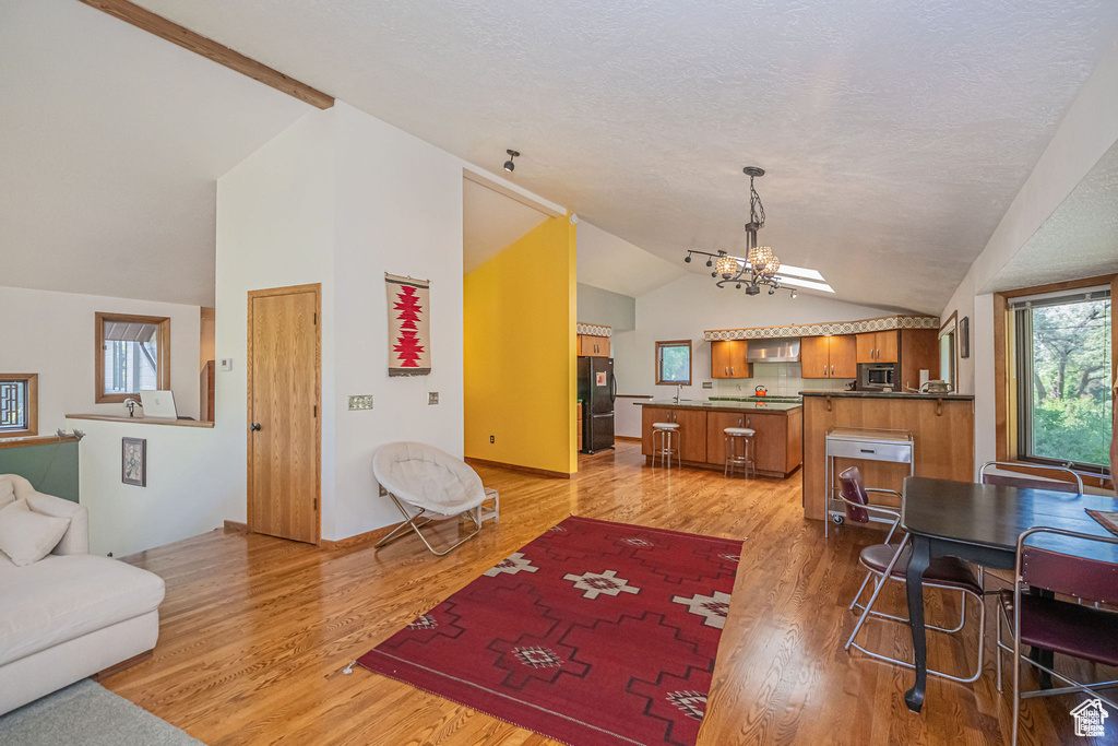 Living area featuring vaulted ceiling, a chandelier, and light wood-type flooring