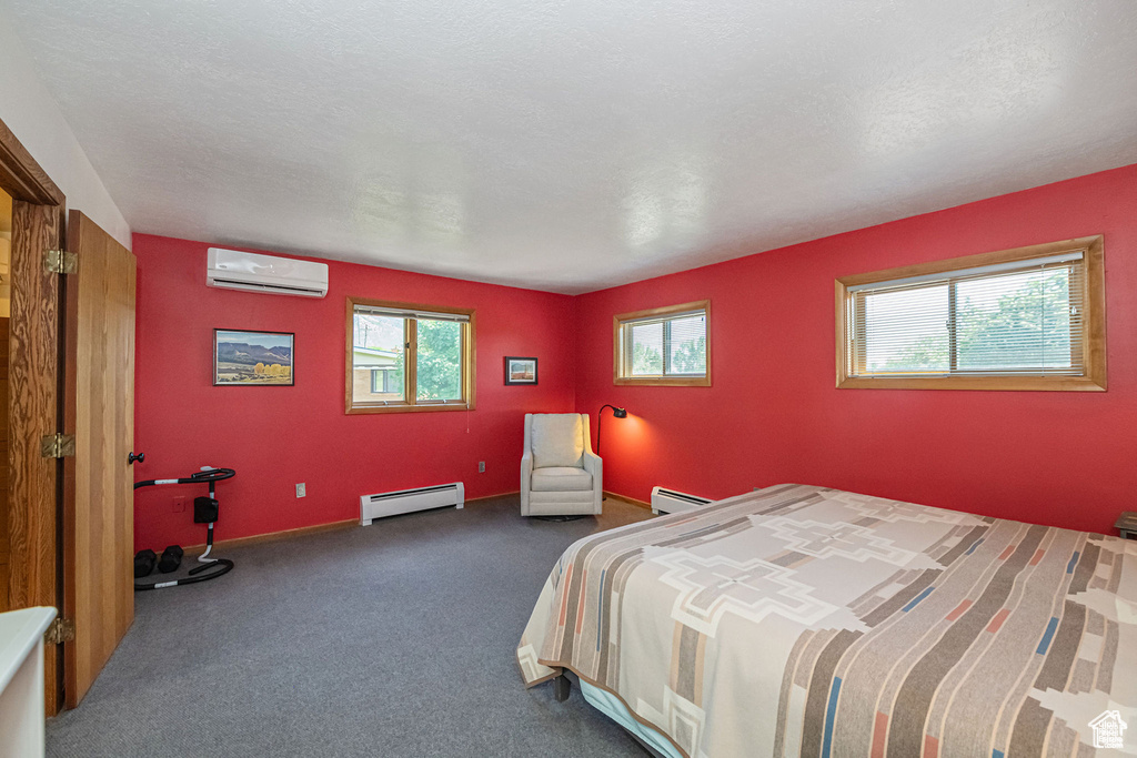 Bedroom featuring a baseboard heating unit, an AC wall unit, and carpet flooring