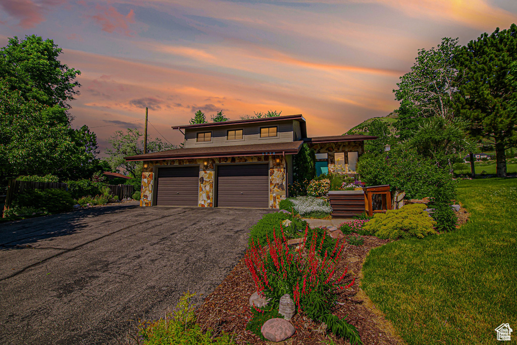 View of front of house featuring stone siding, asphalt driveway, and an attached garage