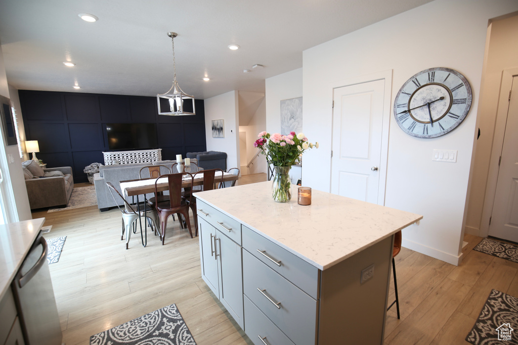 Kitchen with light wood-style floors, a center island, a breakfast bar area, stainless steel dishwasher, and recessed lighting