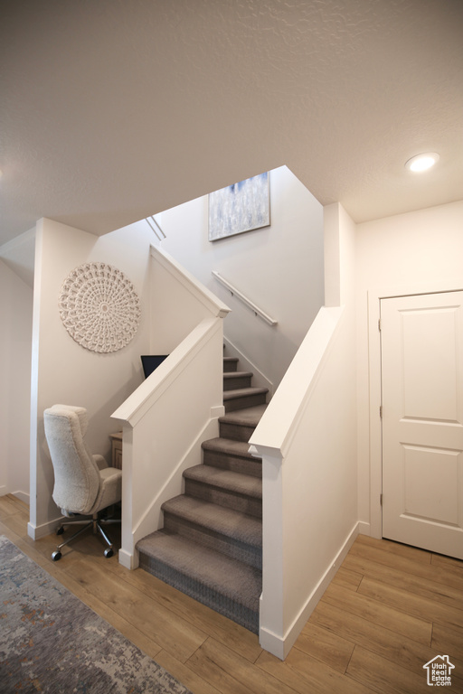 Stairs featuring wood finished floors, baseboards, and recessed lighting