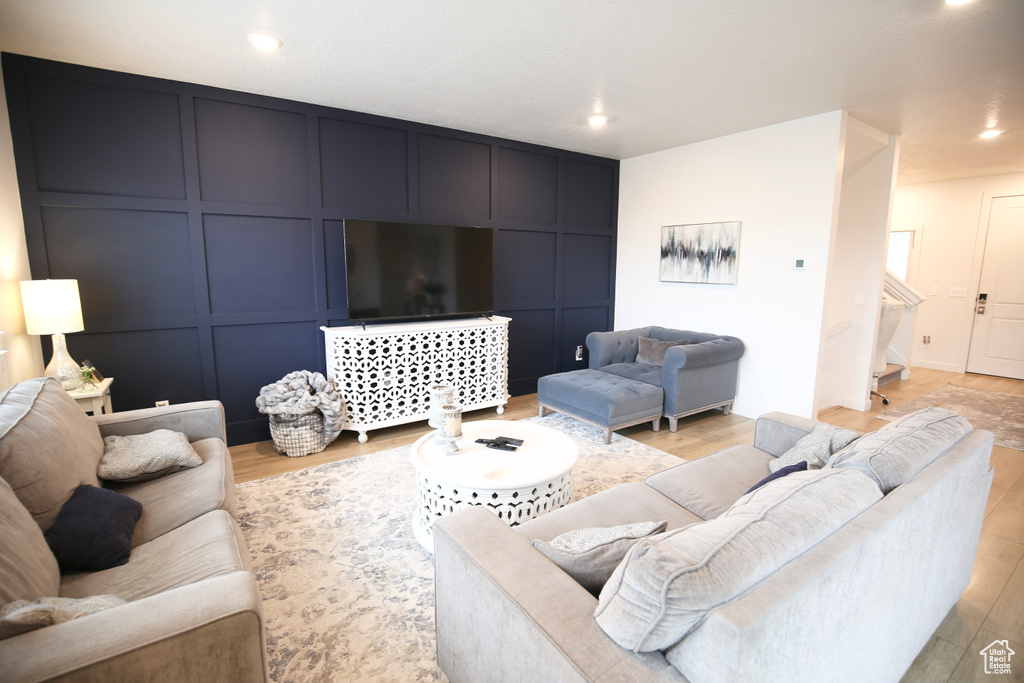 Living room featuring a decorative wall, light wood-style floors, and recessed lighting