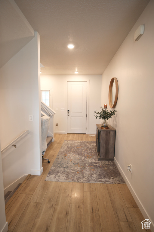 Hallway with stairs, hardwood / wood-style flooring, baseboards, and recessed lighting