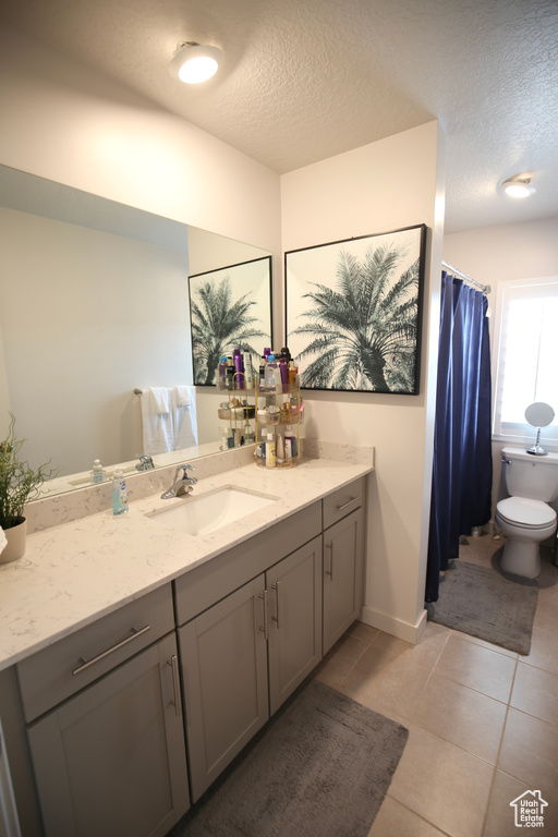 Full bathroom featuring toilet, a textured ceiling, vanity, and tile patterned flooring