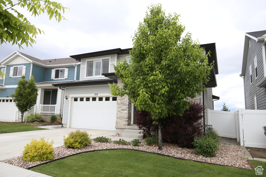 View of front of house featuring a garage, driveway, and fence