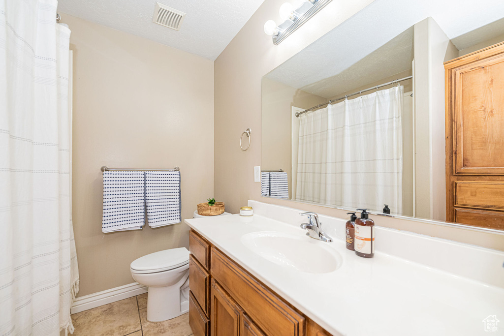Bathroom with tile patterned floors, toilet, vanity, and baseboards