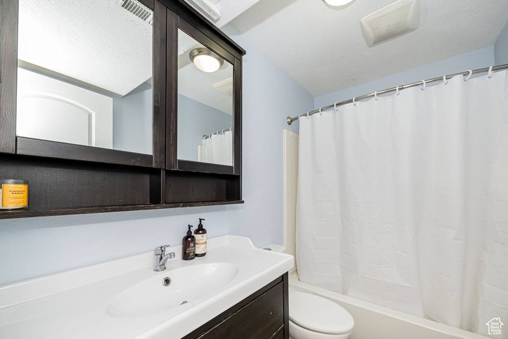 Bathroom with toilet, vanity, and shower / bath combo