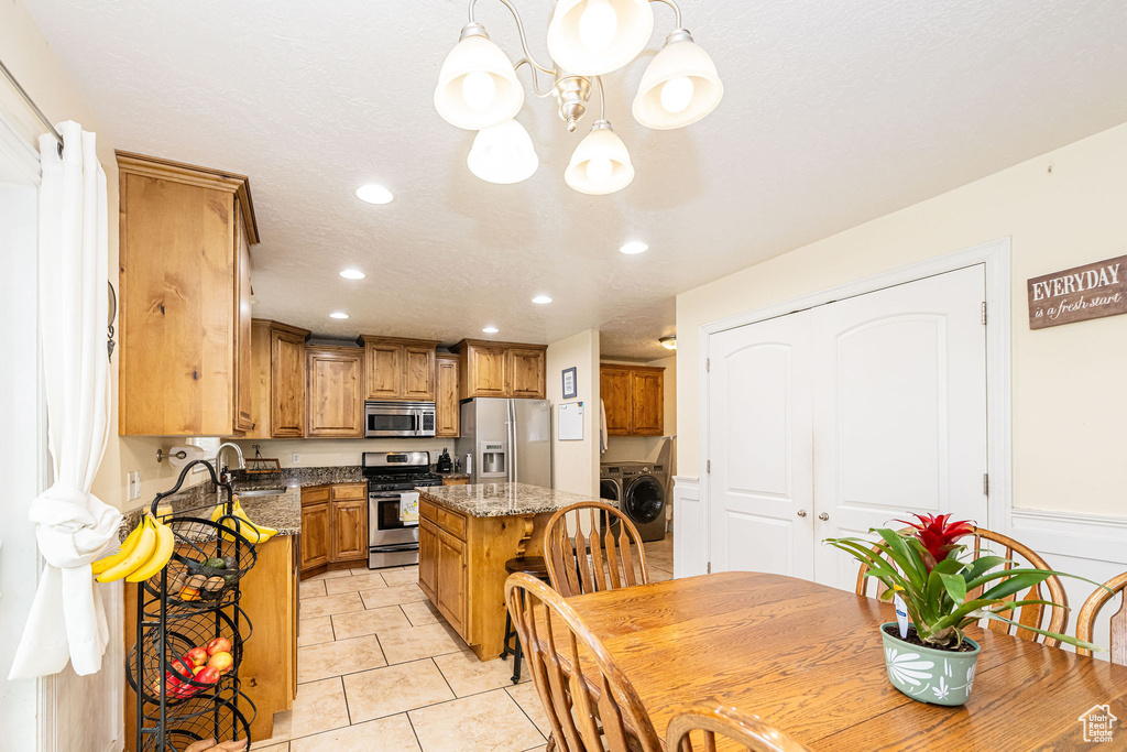 Kitchen with appliances with stainless steel finishes, independent washer and dryer, a chandelier, recessed lighting, and a kitchen island