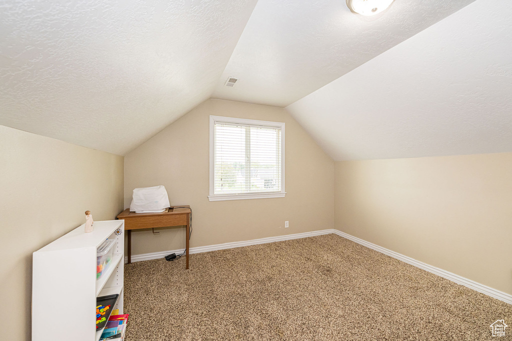 Bonus room featuring lofted ceiling, carpet flooring, baseboards, and a textured ceiling