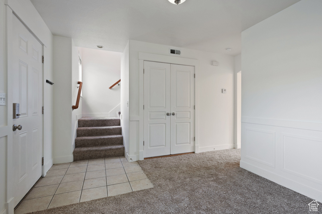 Entryway with light carpet and stairs