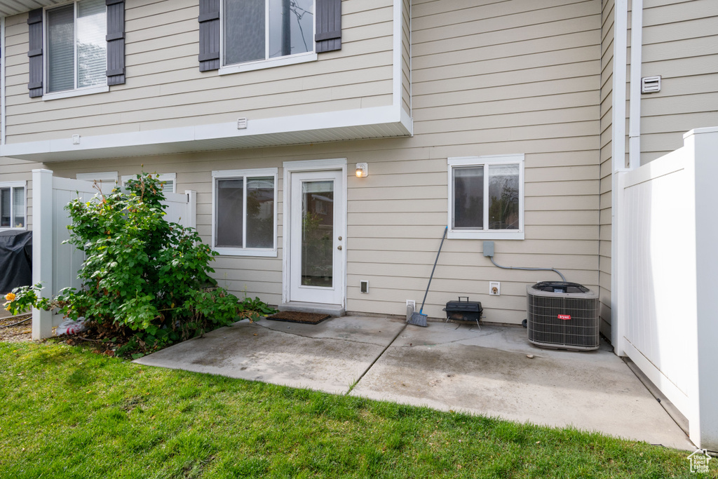 Back of house featuring central AC unit, a patio, and a lawn