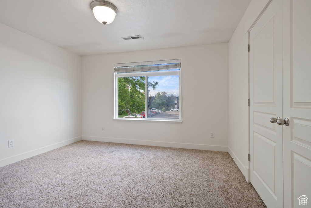 Empty room with light colored carpet and baseboards