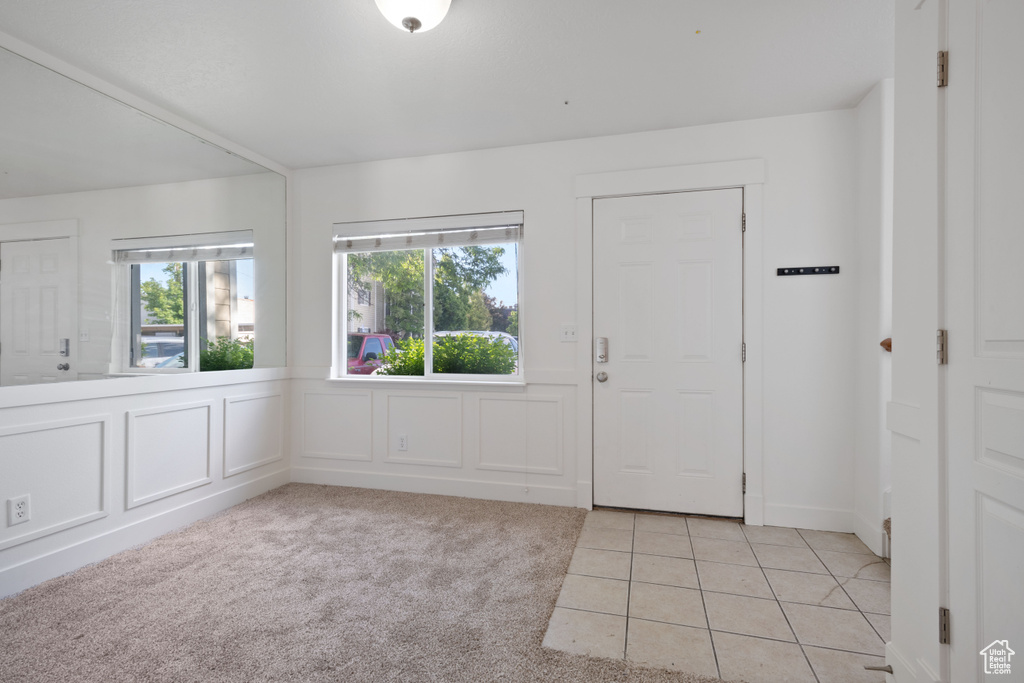Foyer entrance with plenty of natural light, light tile patterned floors, and light carpet