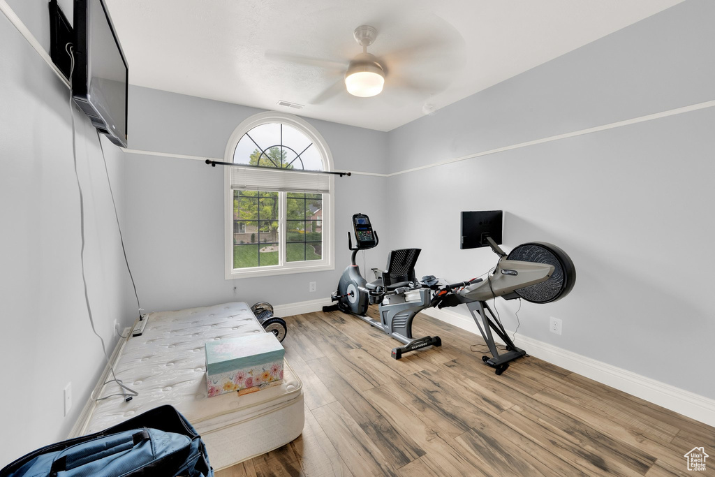 Exercise area with wood finished floors, baseboards, and a ceiling fan
