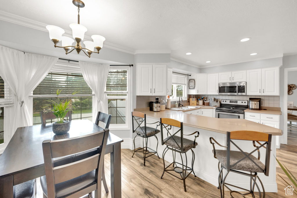 Kitchen featuring stainless steel appliances, a sink, a chandelier, a breakfast bar area, and a peninsula
