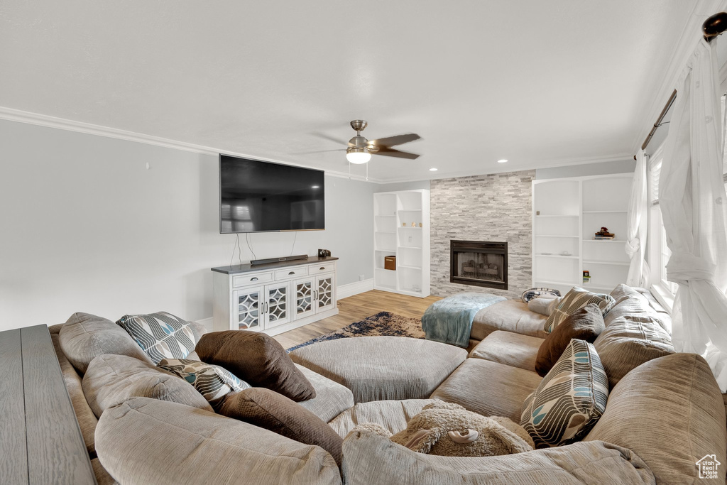 Living room with a ceiling fan, crown molding, light wood finished floors, built in features, and baseboards
