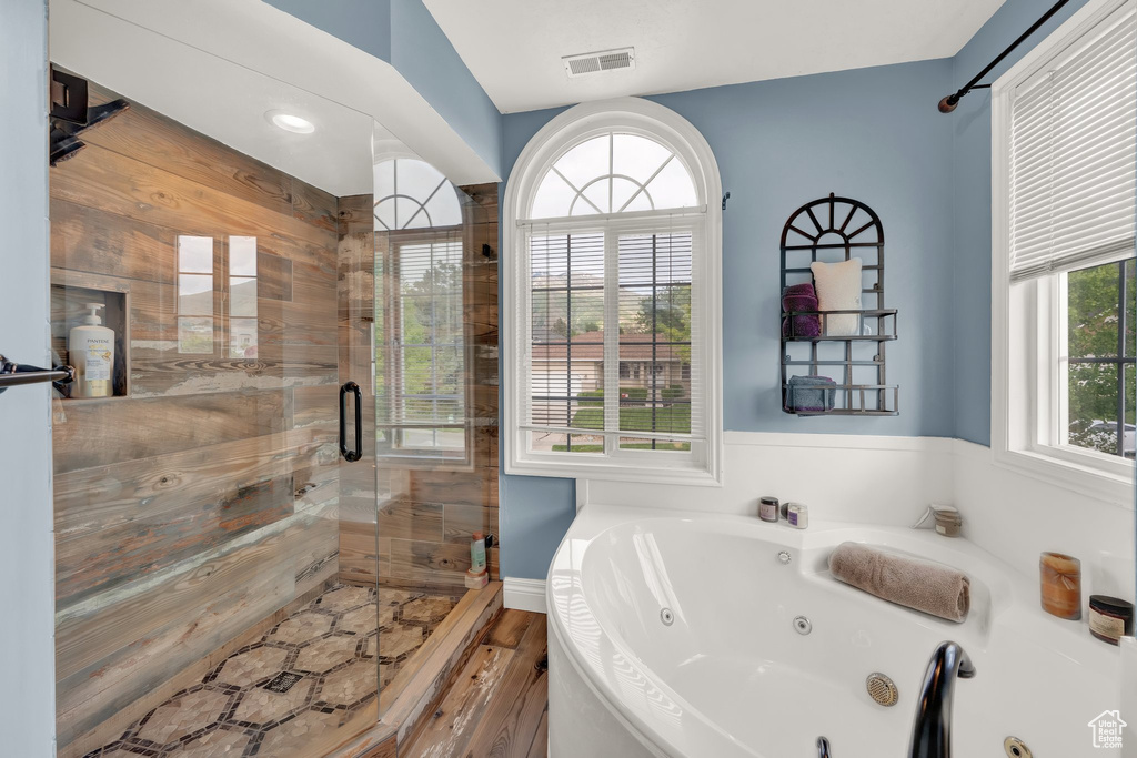 Bathroom with a stall shower, a tub with jets, and wood finished floors