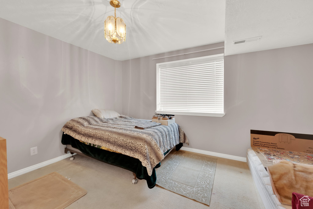 Carpeted bedroom with baseboards and a chandelier