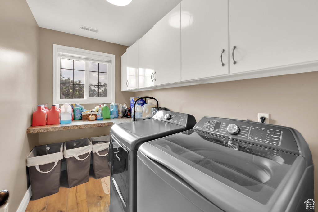 Laundry room featuring cabinet space, washing machine and dryer, and light wood-type flooring