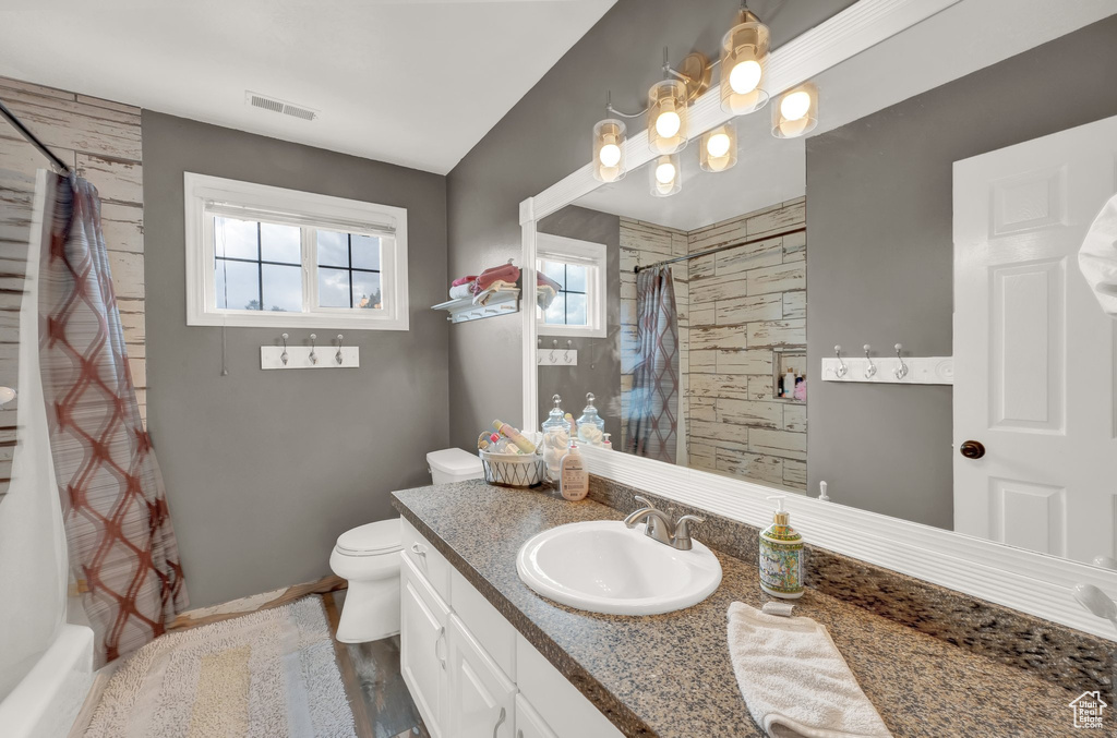 Full bath with curtained shower, toilet, vanity, and baseboards