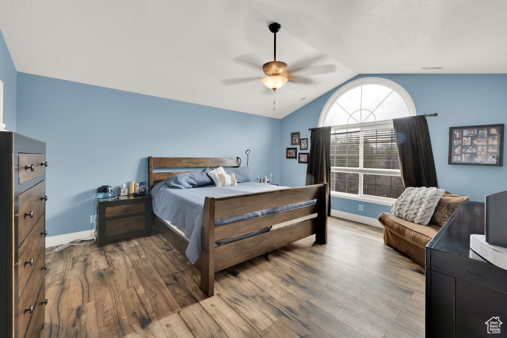 Bedroom with vaulted ceiling, wood finished floors, baseboards, and a ceiling fan
