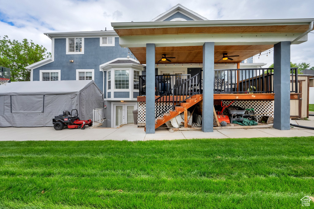 Back of property featuring a ceiling fan, a lawn, stairway, stucco siding, and a patio