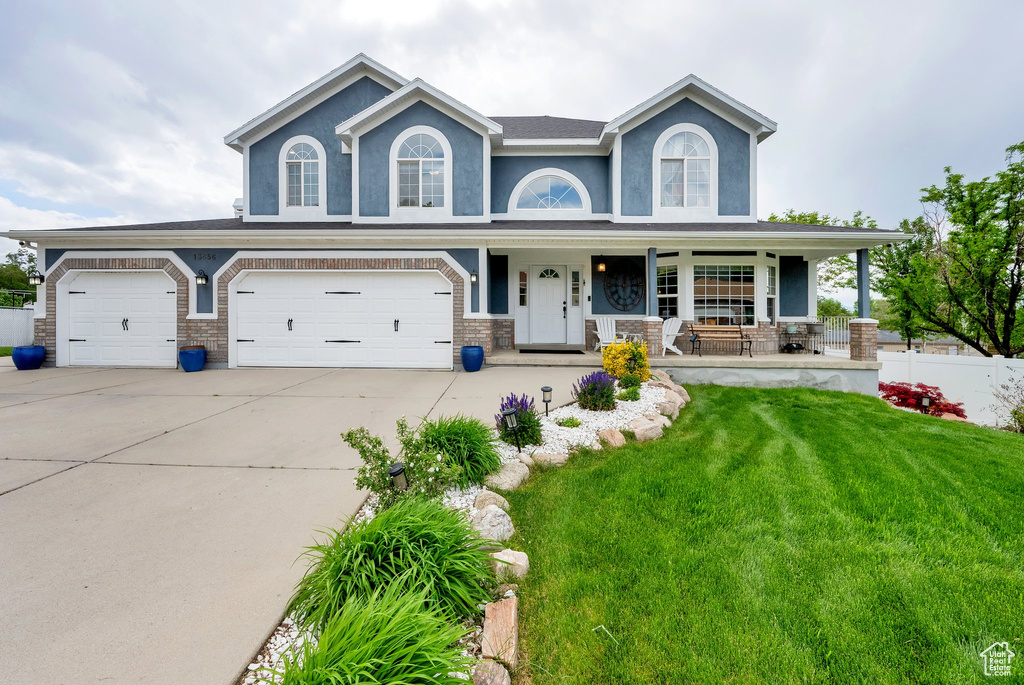 View of front of house with covered porch, driveway, and an attached garage