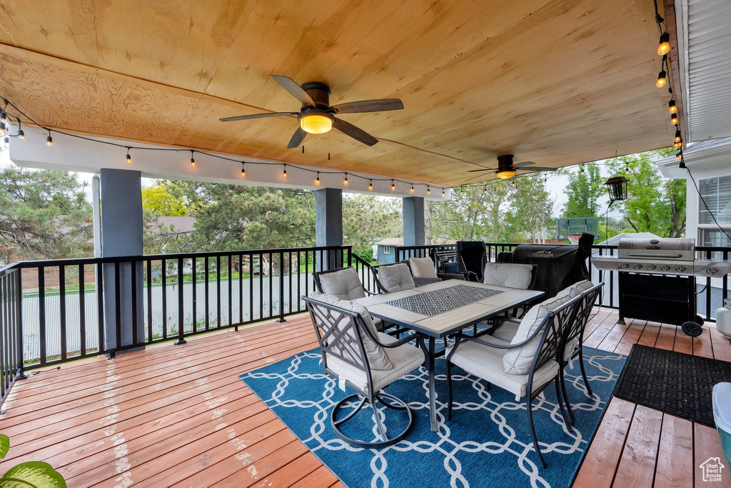 Wooden deck featuring outdoor dining area, a ceiling fan, and area for grilling