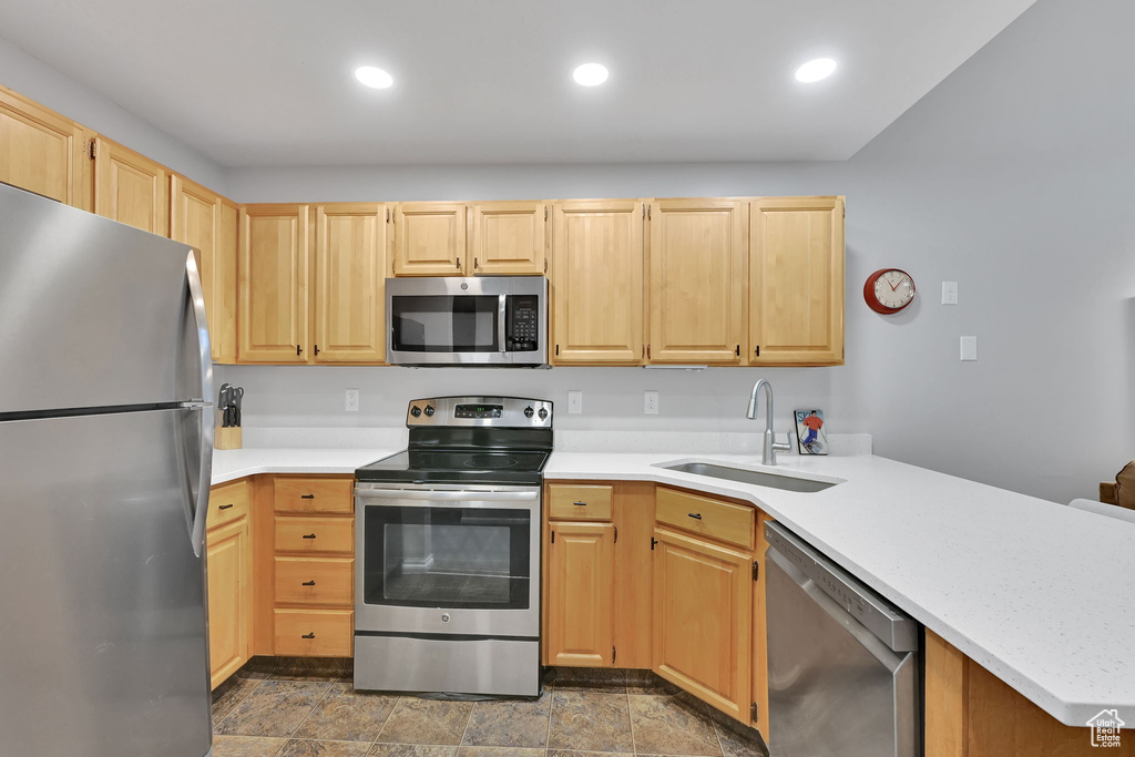 Kitchen featuring stainless steel appliances, a sink, light brown cabinetry, a peninsula, and recessed lighting