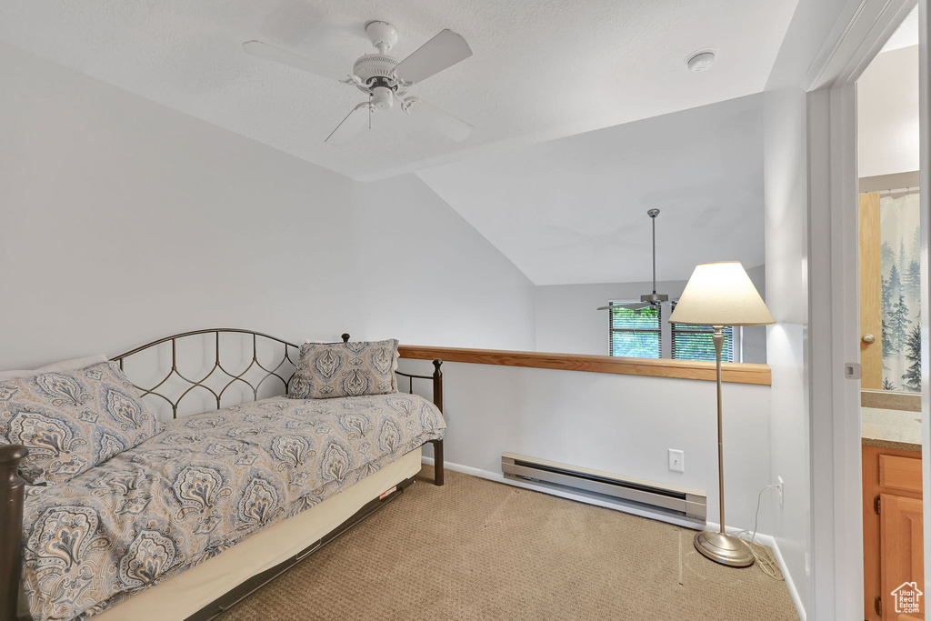 Bedroom featuring a baseboard heating unit, carpet floors, vaulted ceiling, baseboards, and a ceiling fan