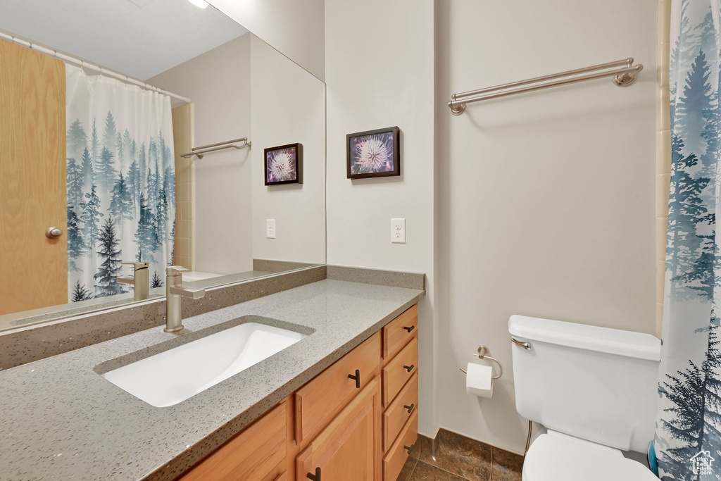Full bath with toilet, vanity, and curtained shower