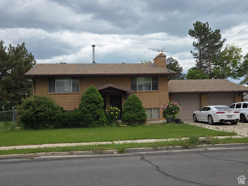 View of front of house with a garage, brick siding, a chimney, and driveway