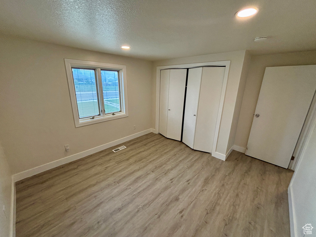 Unfurnished bedroom with light wood-style flooring, baseboards, recessed lighting, and a closet