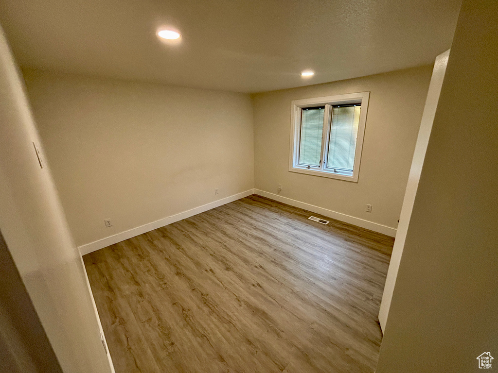 Unfurnished room with wood finished floors, baseboards, and recessed lighting